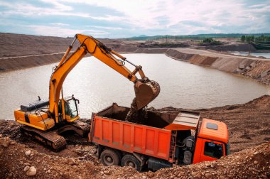 Kazıcı, güneşli bir yaz gününde bir çöp kamyonunun içine kil doldurur.