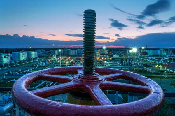 Gate valve on an oil pipe against the background of an oil pumping station