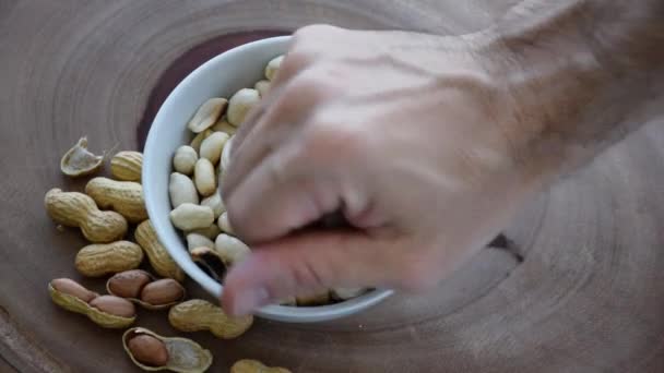 Les gens cueillent des cacahuètes à partir d'une petite partie au centre. Fond bois. — Video