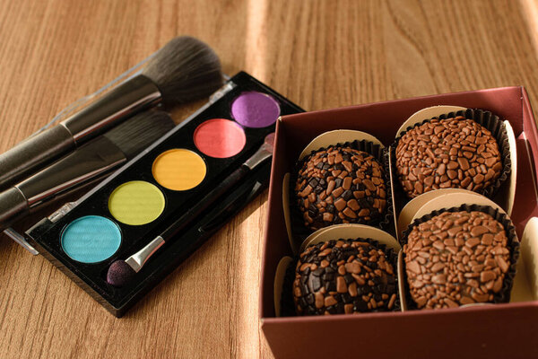 Коробка с бригадирами и макияжем освещается солнцем.