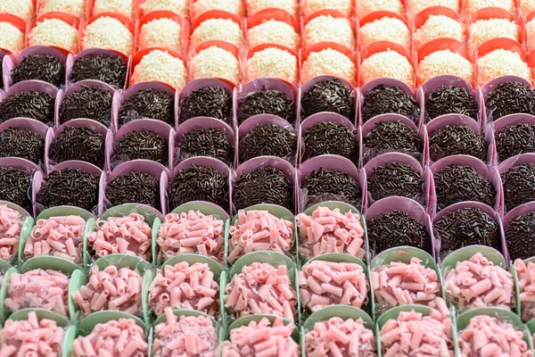 Various types of brigadiers organized in rows. Chocolate, red fruit and white chocolate brigadiers (side view).