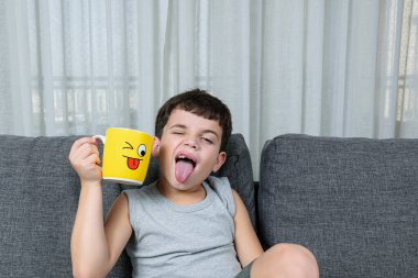 7 yaşında bir çocuk, sarı fincanın yüzünü taklit ediyor.).