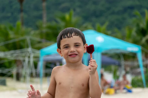Çocuk plajda buzlu şeker gösteriyor.