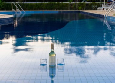 Havuz suyuna batırılmış bir şişe beyaz şarap (arka plandaki tüm havuz)).