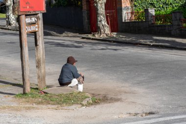 Campos do Jodao, Sao Paulo / Brazil, 20 Temmuz 2019 'da kaldırımda oturan araba bakıcısı.