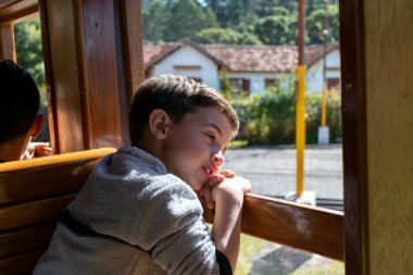 Kafası trenin camına dayanmış gezintiyi izleyen bir çocuk..