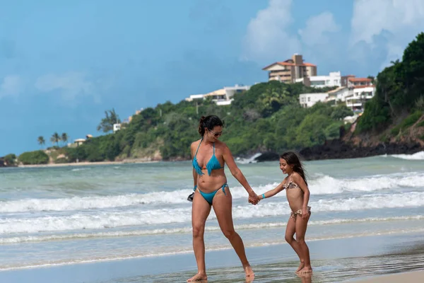 Natal, Cotovelo plajı, Rio Grande do Norte, Brezilya, 26 Temmuz 2019: Anne kızına gülümsüyor ve Cotovelo plajında yürüyor.