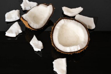 Aynalı siyah arka planda kurutulmuş hindistan cevizi parçaları..