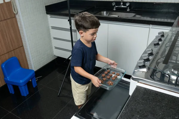 Boy taking glass pan to the oven.