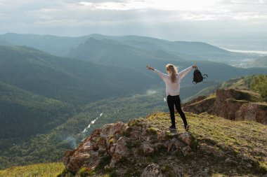 Dağın tepesindeki gezgin uzaklığa bakar.
