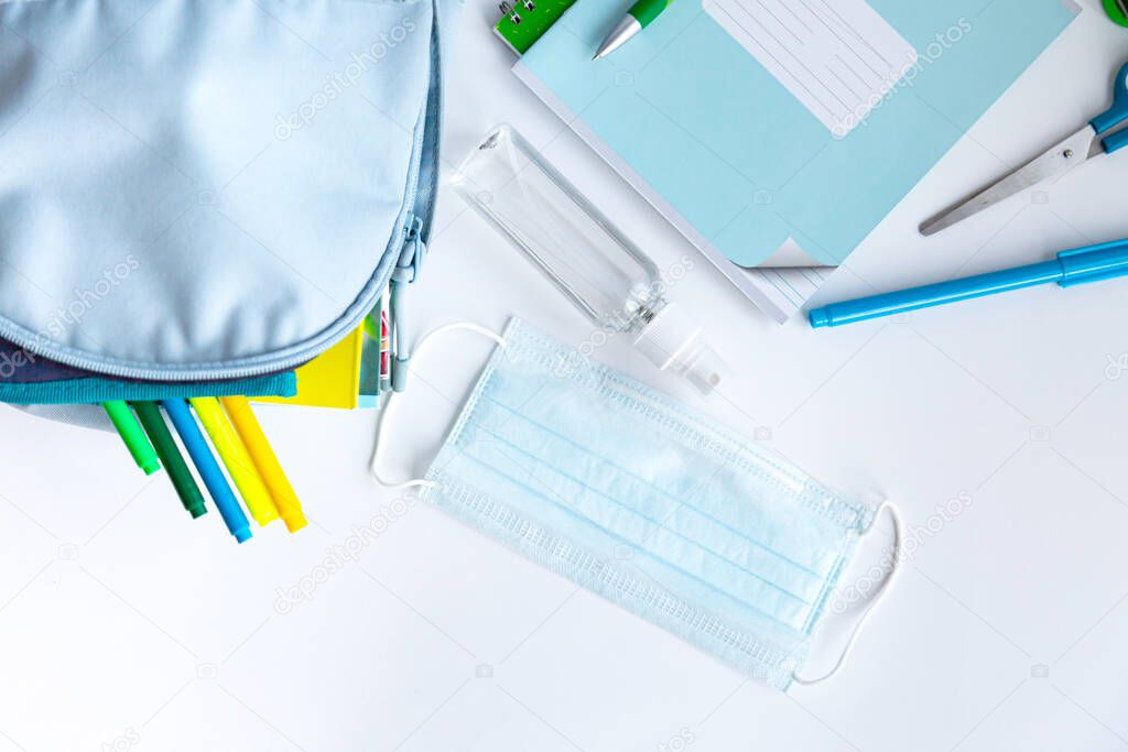 Back to school after coronavirus pandemic. Backpack, stationery, antiseptic, face mask on a white background. (notebooks, pens, felt-tip pens, scissors, stapler, sanitizer, covid-19) 