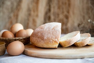 Ekmek, süt ve tuz dolu yumurta ve ahşap tabaklarda, arka planda sıcak renklerde..