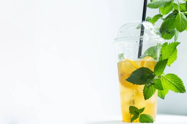 Beyaz arka planda plastik bardakta buzlu limon ve limon kremi ile yeşil çay.