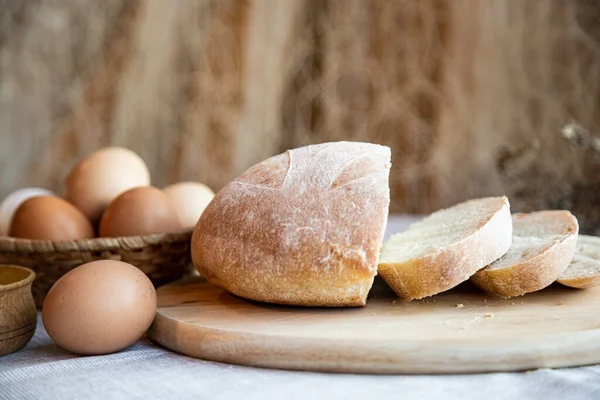 Ekmek, süt ve tuz dolu yumurta ve ahşap tabaklarda, arka planda sıcak renklerde..