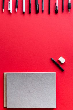 Kırmızı arka planda kalemler ve kalemler var. Kopyalama alanı olan üst görünüm