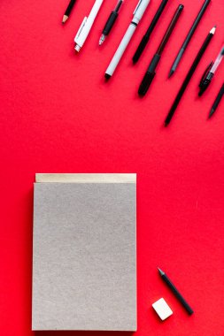 Kırmızı arka planda kalemler ve kalemler var. Kopyalama alanı olan üst görünüm