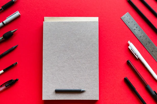 メモ帳は赤い背景にペンと鉛筆 コピースペース付きのトップビュー — ストック写真