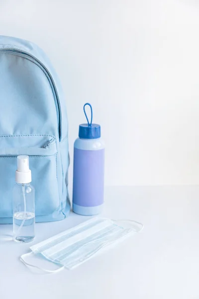 Backpack, water bottle, face mask and antiseptic on a white background. Walking concept.