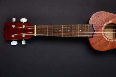 Siyah arkaplanda, kopyalama alanı olan koyu ahşap ukulele gitar.