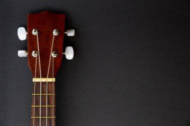 Siyah arkaplanda, kopyalama alanı olan koyu ahşap ukulele gitar.