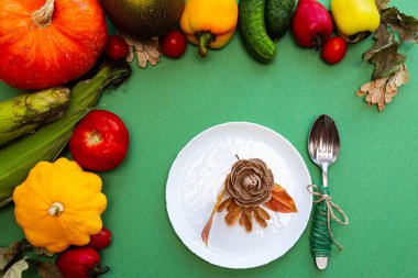Sonbahar yapraklı beyaz tabak ve çatal bıçak takımı ve yeşil arka planda sebzeler. Şenlikli sonbahar konsepti.