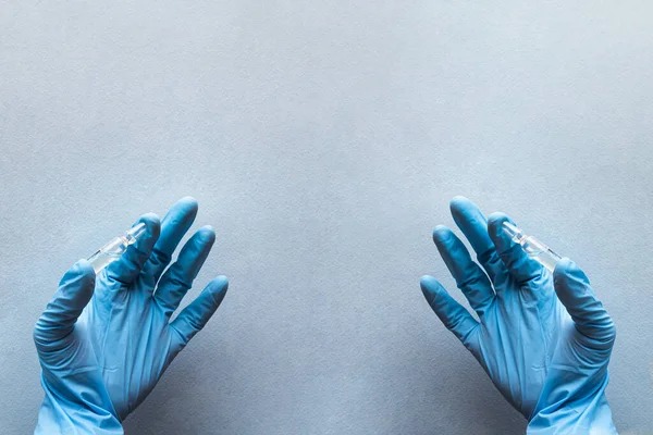 A doctor in a medical gloves holds a vial with a vaccine. Health care concept