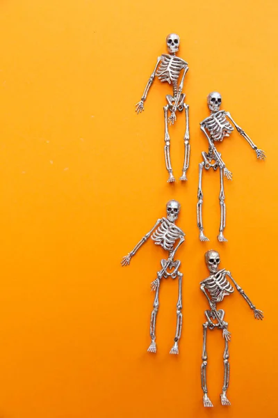 Skeletons in silver and gold are dancing on an orange background. Halloween and Day of the Dead concept — Stock Image Skeletons Silver Gold Dancing Orange Background Halloween Day Dead Concept Royalty Free Stock Images