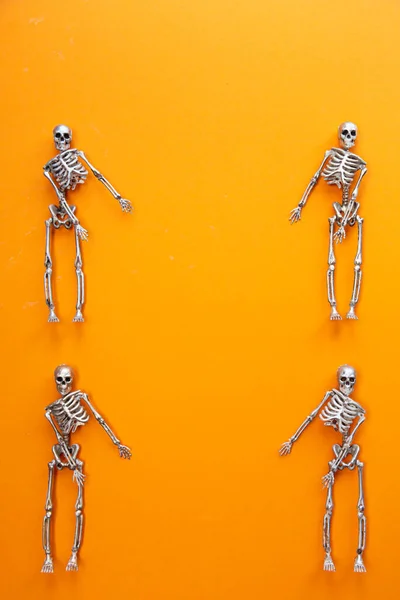 Skeletons in silver and gold are dancing on an orange background. Halloween and Day of the Dead concept — Stock Image Skeletons Silver Gold Dancing Orange Background Halloween Day Dead Concept Stock Picture