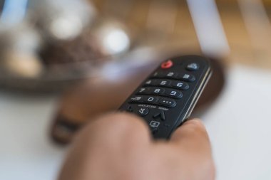 Oturma odasında televizyon izlemek için uzaktan kumandayı tutuyorum.