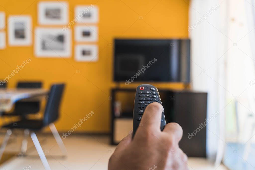 Hand holding remote control for watching tv in the living room