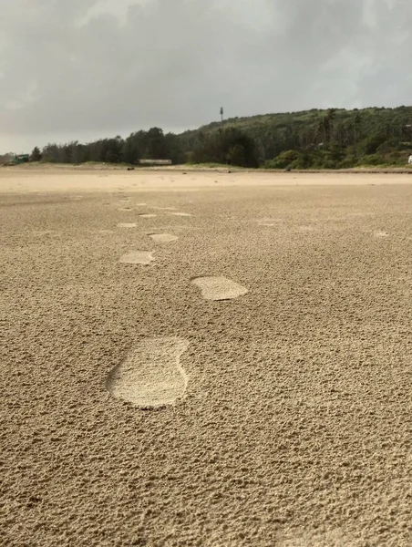 Muson mevsiminde Mandrem sahilinde, Goa 'da, Hindistan' da ayak izleri. Kumsalda bulutlu gün ayak izleri