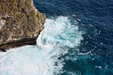 Okyanus dalgalarının Nusa Penida Adası, Bali, Endonezya 'daki kayalara çarpması dramatik bir manzara.