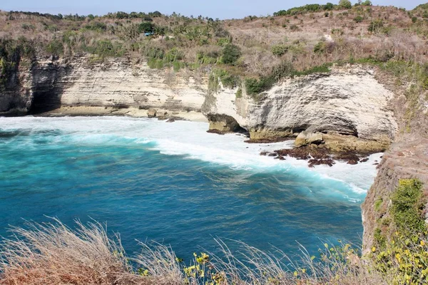 Dik uçurumların dibindeki kayalık kıyılarda dalgalar kopuyor, Nusa Penida, Endonezya