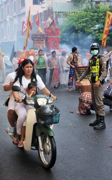 Phuket Town / Tayland - 7 Ekim 2019: Phuket Vejetaryen Festivali veya Dokuz İmparator Tanrısı Festivali motosikletli bir kadın ve çocukla, bir polis memuru ve renkli giysiler içinde Taoist fanatiklerle geçit töreni