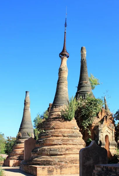 Myanmar, Inle Gölü 'nün güneybatısındaki In Dien' de yeşil bitkilerle büyüyen eski taş pagoda kalıntıları.