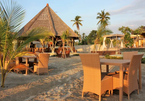 Nusa Penida Adası, Bali / Endonezya - 19 Eylül 2019: Sazlı çatılı ve palmiye ağaçlı Bambu çardağı, tropik tatil beldesinde masa ve sandalyeler