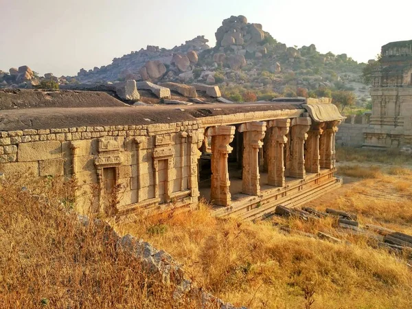 Gündoğumunda Achyuta Raya Tapınağı 'ndaki harabe duvarları ve sütunlar. Arka planda ise Hampi, Karnataka, Hindistan' daki Rocky Hill.