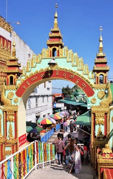 Turistler ve dini hacılar Kyaiktiyo Pagoda (Altın Kaya), Mon State, Myanmar yakınlarındaki bir kapı altında yürüyorlar
