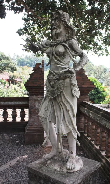 Balinese stone statue of demon on a pedestal at Titra Gangga, Water Palace in Bali, Indonesia