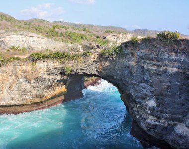 Mavi yeşil okyanus suyu Endonezya, Nusa Penida, Broken Beach 'te doğal kemerin altından akıyor.