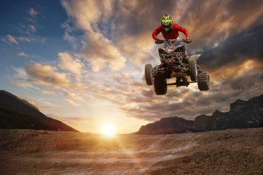 Man on atv jump on the trail during sunset. clipart