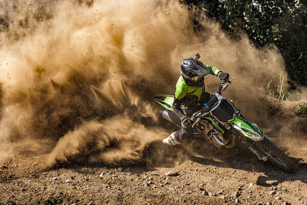 Motocross rider creates a large cloud of dust and debris