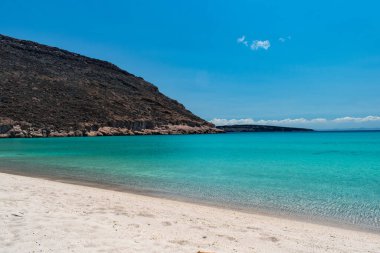 Meksika, La Paz 'daki Espiritu Santo Adası' nda kristal berrak su ve dağlarla dolu bir plaj manzarası.