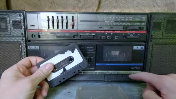 男の手は古いテープレコーダーにアナログテープを挿入します テープが回転し始める レトロなスタイルの80 90年 アナログデバイス — ストック動画