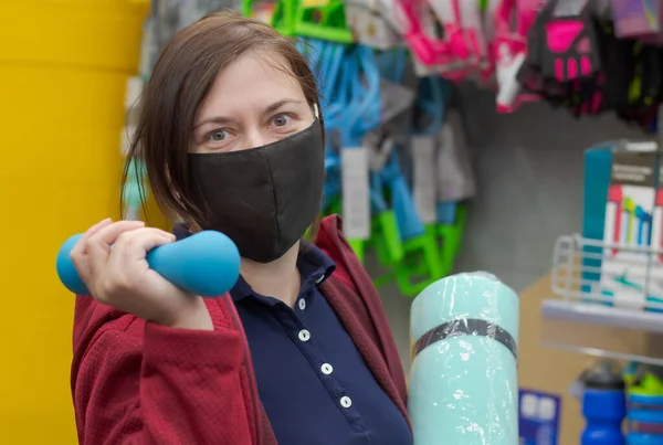 Spor malzemeleri mağazasında tıbbi maske takan bir kadın.. 