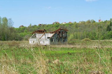Kuru çimenler, paslı çatısı, gökyüzü ve tepesi olan eski bir ev..