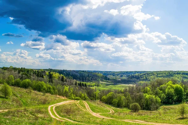 Uzaklara ve dramatik bulutlara uzanan bir tepe manzarası.