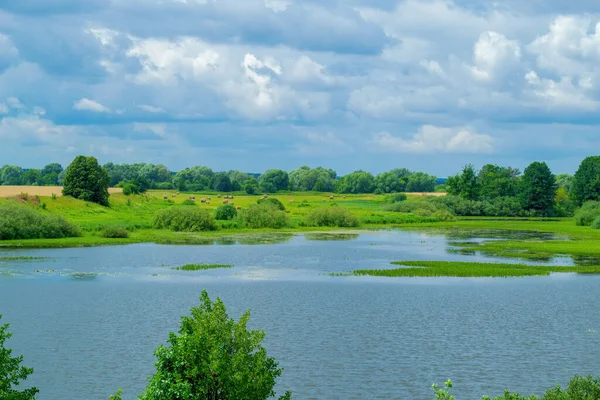 Thick clouds float over the lake. Theres a haystack in the background.