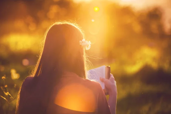 在日落时读圣经的女孩 免版税图库照片