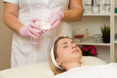 Kozmetik uzmanı, süngere mikiler suyu uyguluyor. Yüzü temizliyorum. Kozmetik uzmanı randevusunda.